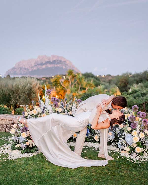 Coppia sposa in giardino fiorito, tramonto romantico.