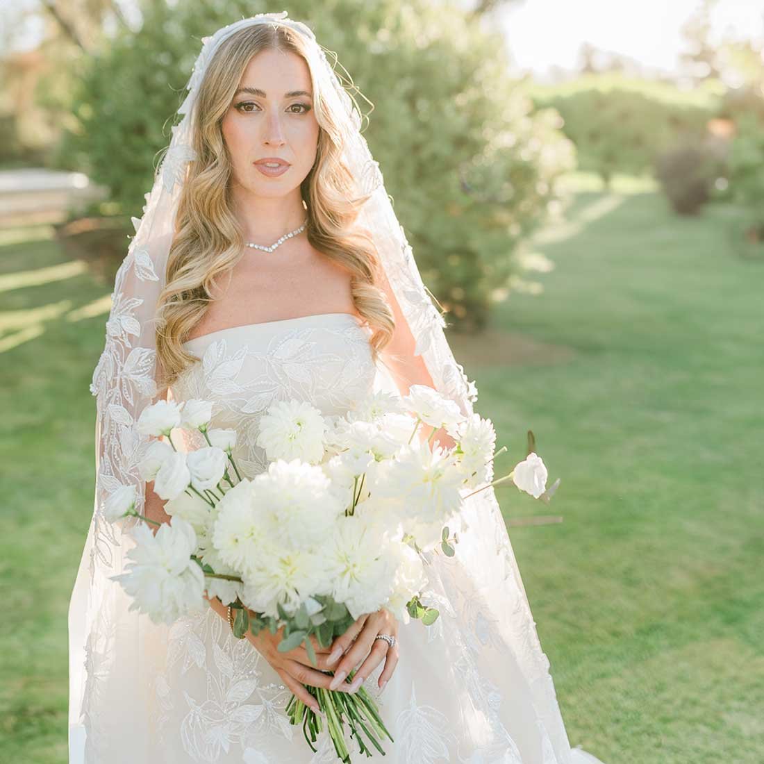 Sposa con bouquet di fiori bianchi in giardino.